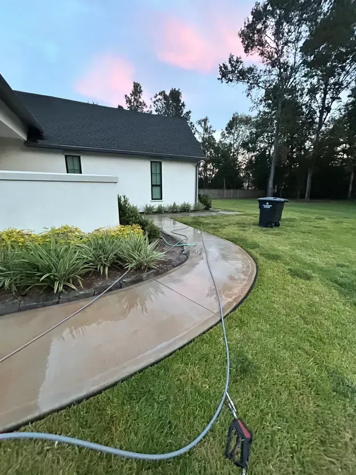 A pressure washer is being used to clean a sidewalk in front of a house.