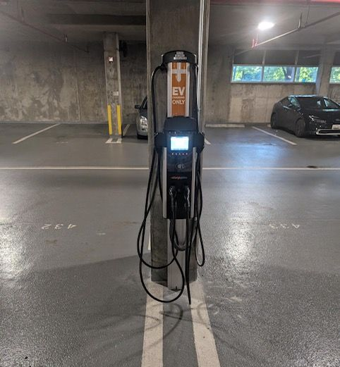An electric vehicle charging station mounted on a concrete pillar in a parking garage.