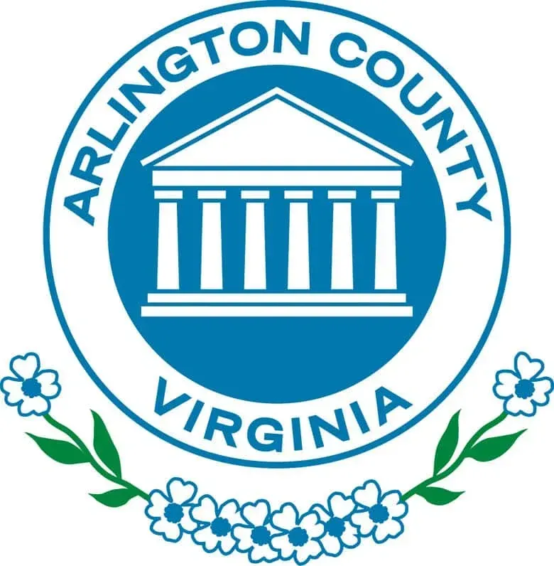 Seal of Arlington County, Virginia, featuring a white temple on a blue circle, framed by green stems and dogwood flowers.