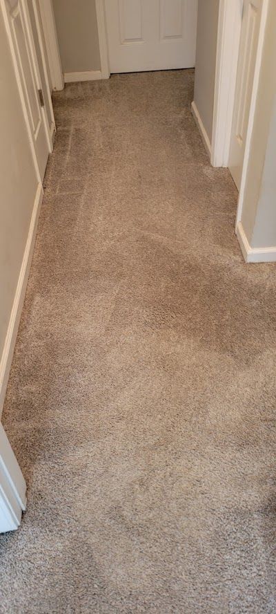 A hallway with a carpeted floor and a door.