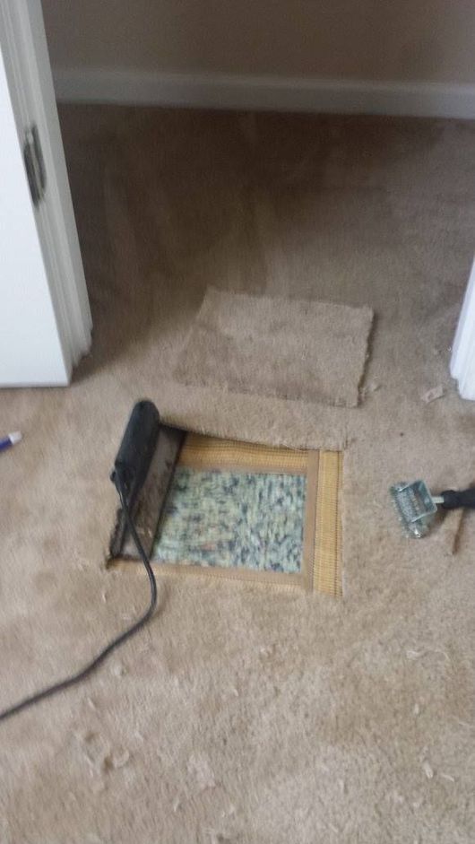 A hole in the floor of a room with a vacuum cleaner.