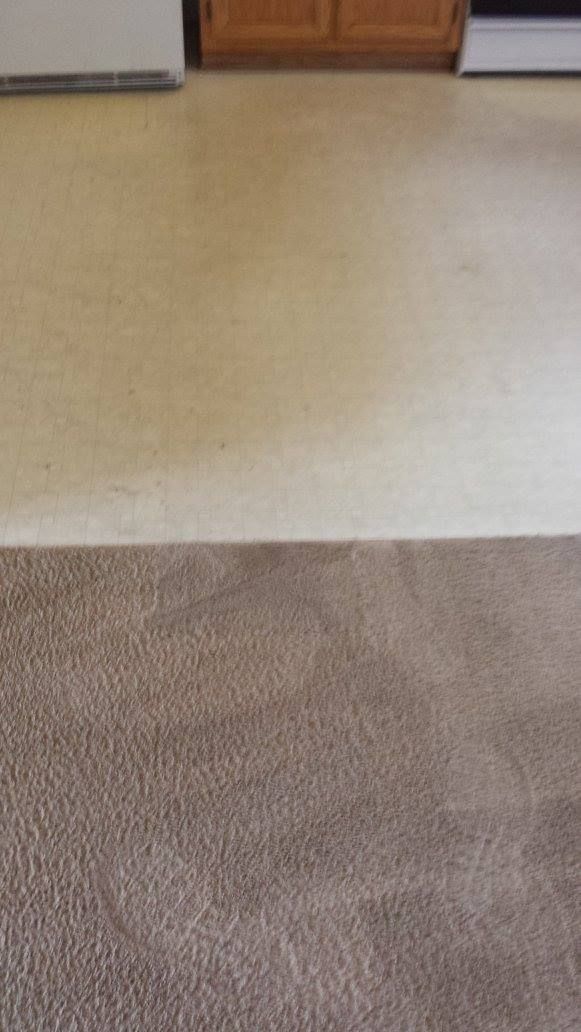 A kitchen floor with a rug and a stove.