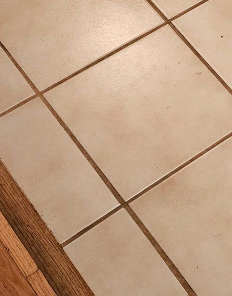 Off-white tile floor with brown grout lines. A small section of wooden floor is visible on the bottom left.