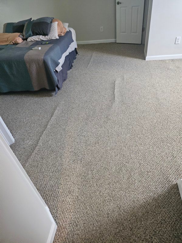 Bedroom with a wrinkled carpet, a bed with blue and gray bedding, and a closed white door.