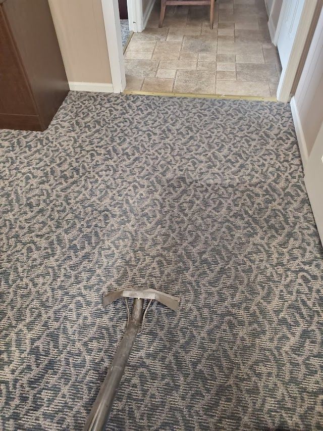 A vacuum cleaner is cleaning a carpet in a hallway.