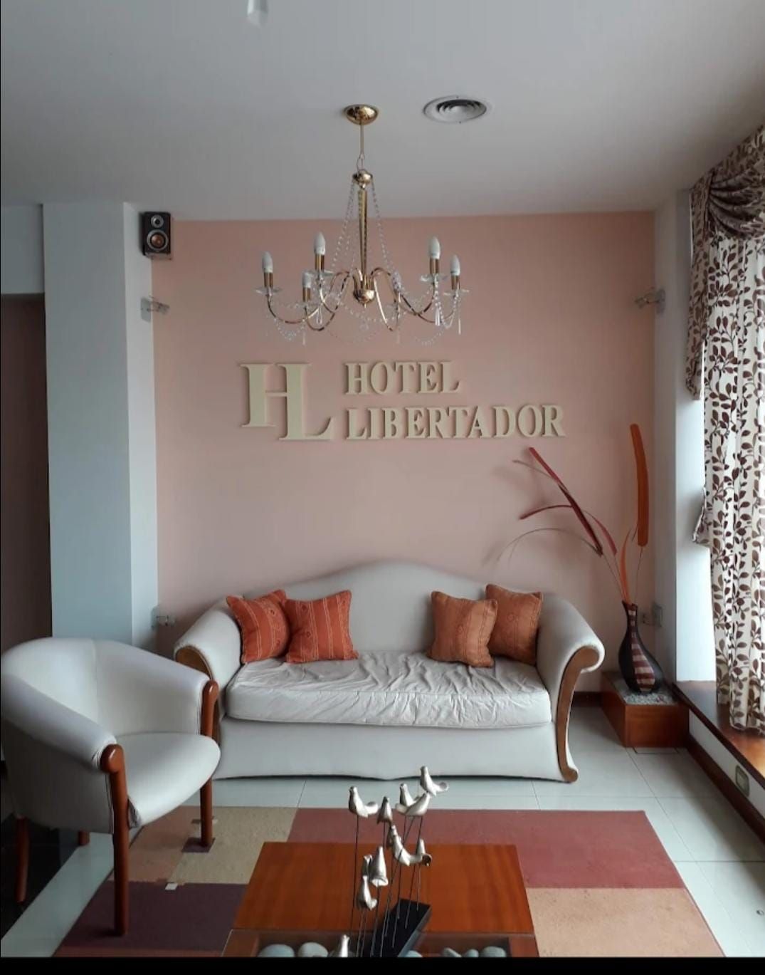 Cama con sábanas y almohadas blancas, pétalos de rosas rojas esparcidos en la superficie.