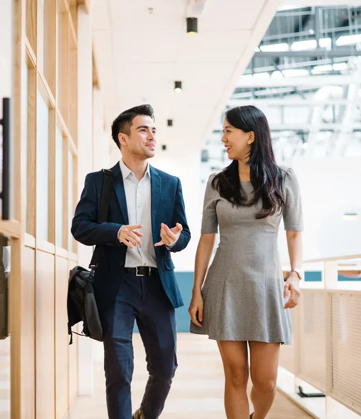 A woman is sitting at a table reading magazines and talking on a cell phone.