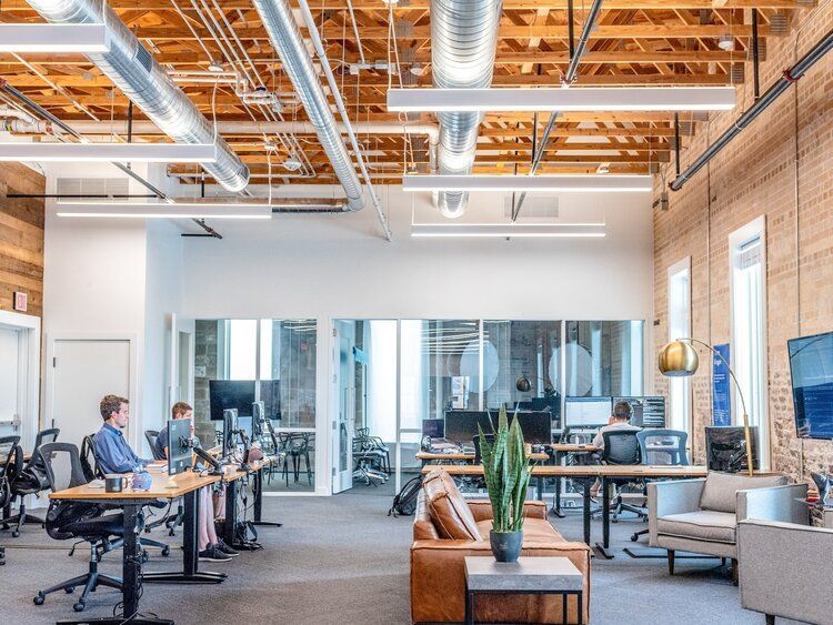 A group of people are sitting at desks in an office.