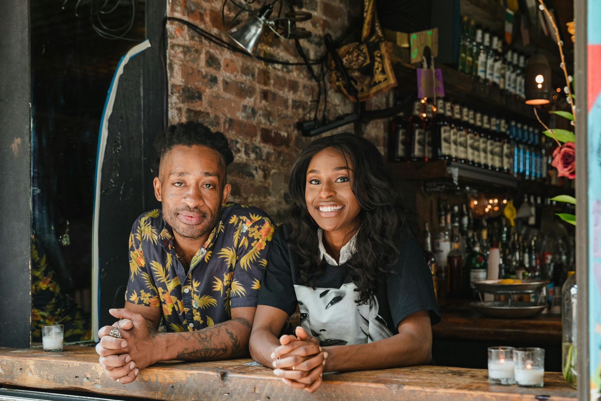 A man and a woman are sitting at a bar holding hands