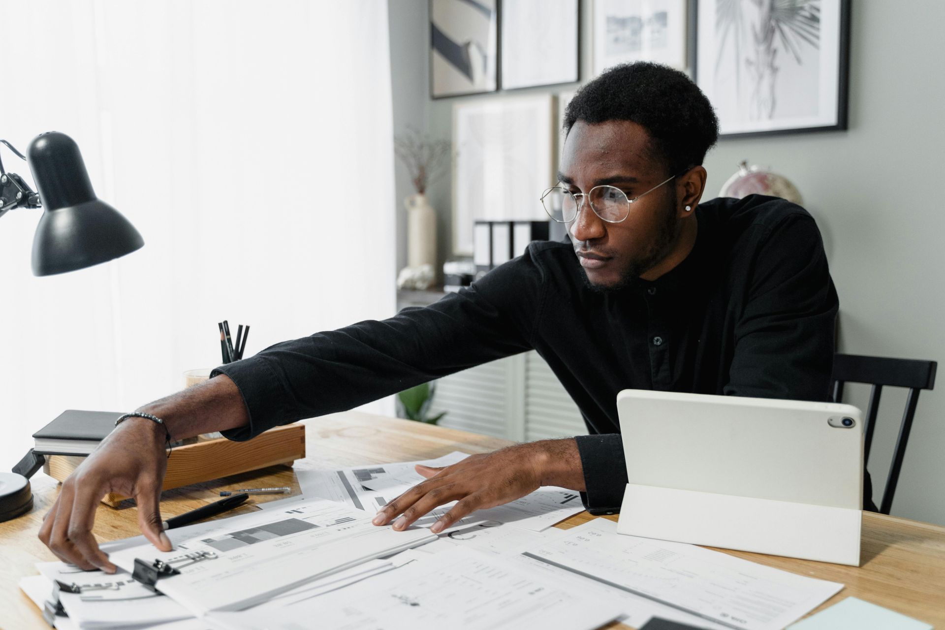 A man is sitting at a desk with papers and a tablet. about to start payroll for his business