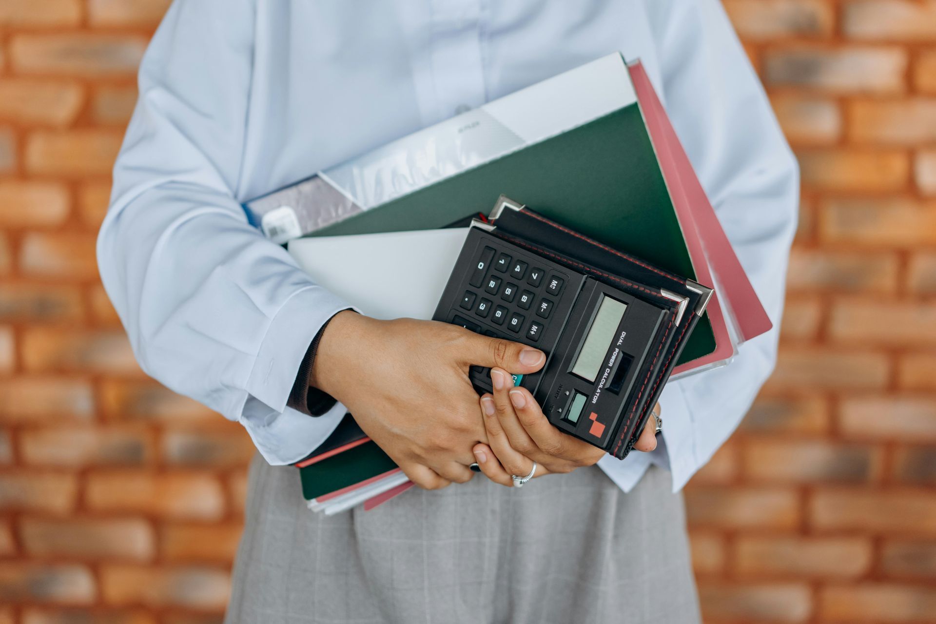 A woman is holding a stack of folders and a calculator