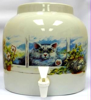 Cream-colored ceramic water dispenser with a cat peeking through a window. Blue, green, and floral accents. White spigot.