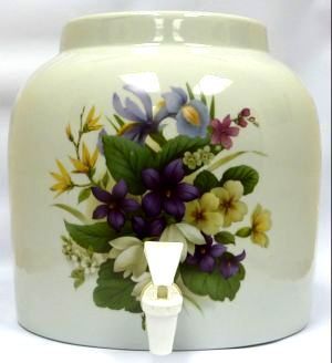 Cream-colored ceramic water dispenser with floral design. Features a white spigot and a rounded shape.