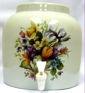 Ceramic water dispenser with floral bouquet decoration and white spigot.