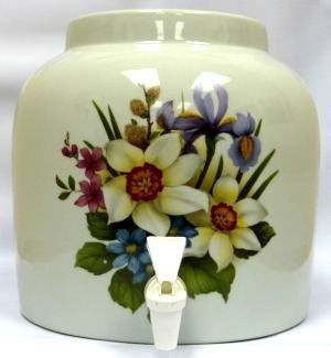Cream-colored ceramic water dispenser with floral design and white spigot.