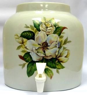 Ceramic beverage dispenser, cream-colored with a magnolia floral design, white spigot.