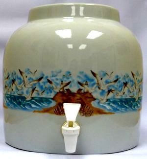 Cream ceramic water dispenser with sea gull design and white spout.