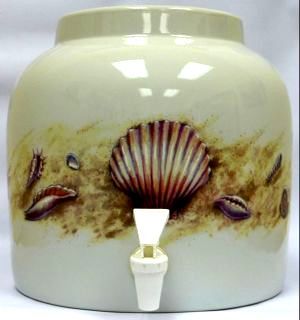 Ceramic water dispenser with a seashell design and spigot on a white background.