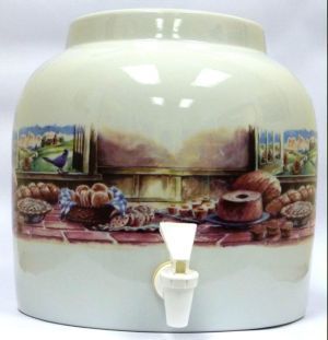 Cream-colored ceramic beverage dispenser with scene of baked goods, spigot, and painted countryside view.