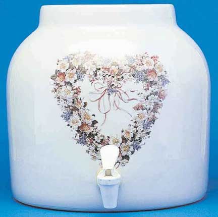 White ceramic water dispenser with a floral heart design and a spigot.