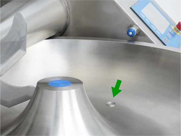 A stainless steel machine with a green arrow pointing to a hole