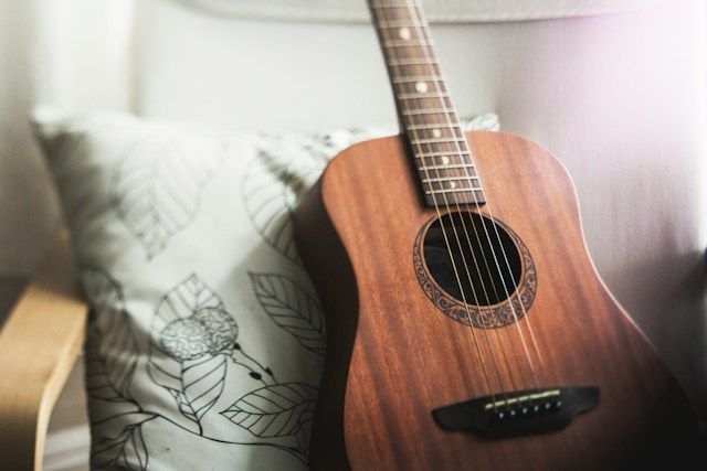 Acoustic guitar resting indoors in Lakewood CA, funeral homes use personal items