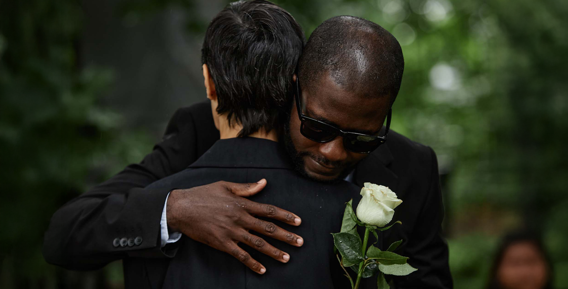 a woman is holding a red rose in front of a coffin .