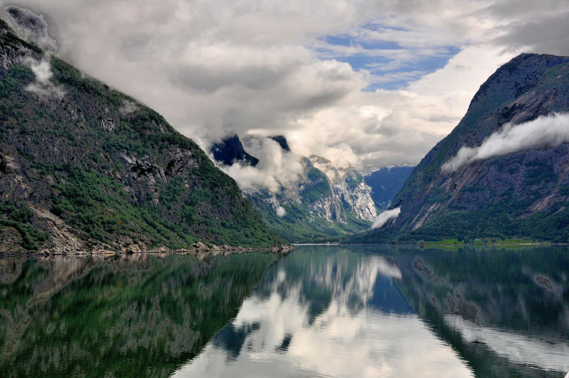 Fjord landscape: mountains flank still water, reflecting clouds and peaks.