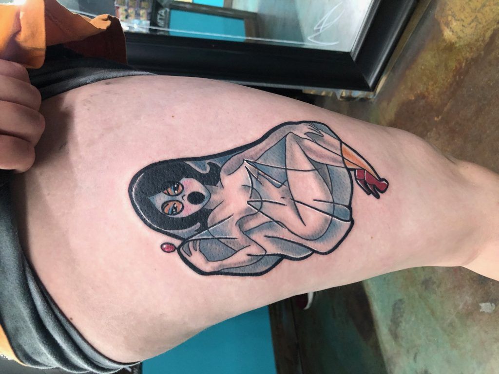 A person has a tattoo of a woman on their thigh.