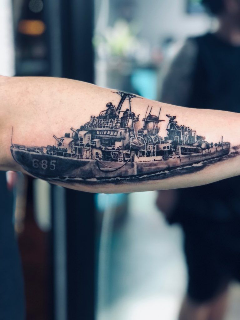 A person has a tattoo of a ship on their arm