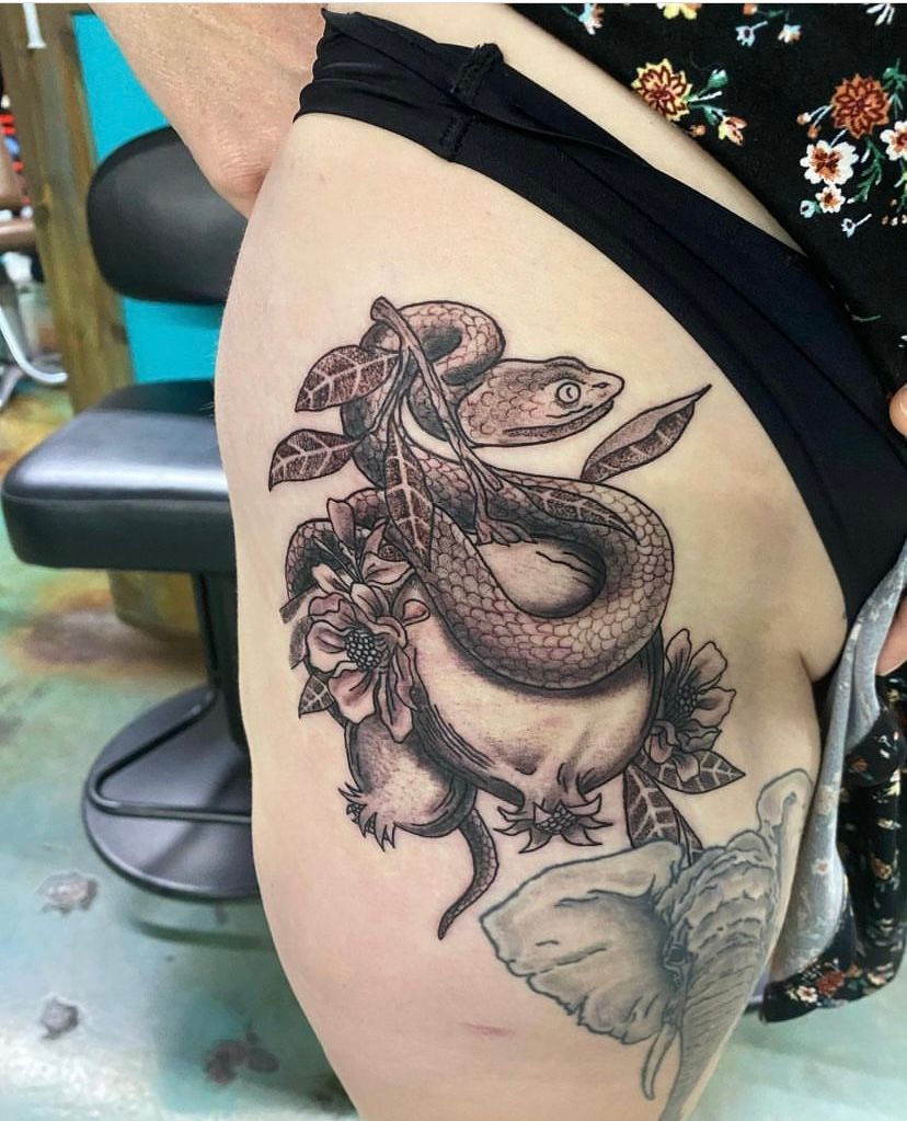 A woman has a tattoo of a snake on her hip