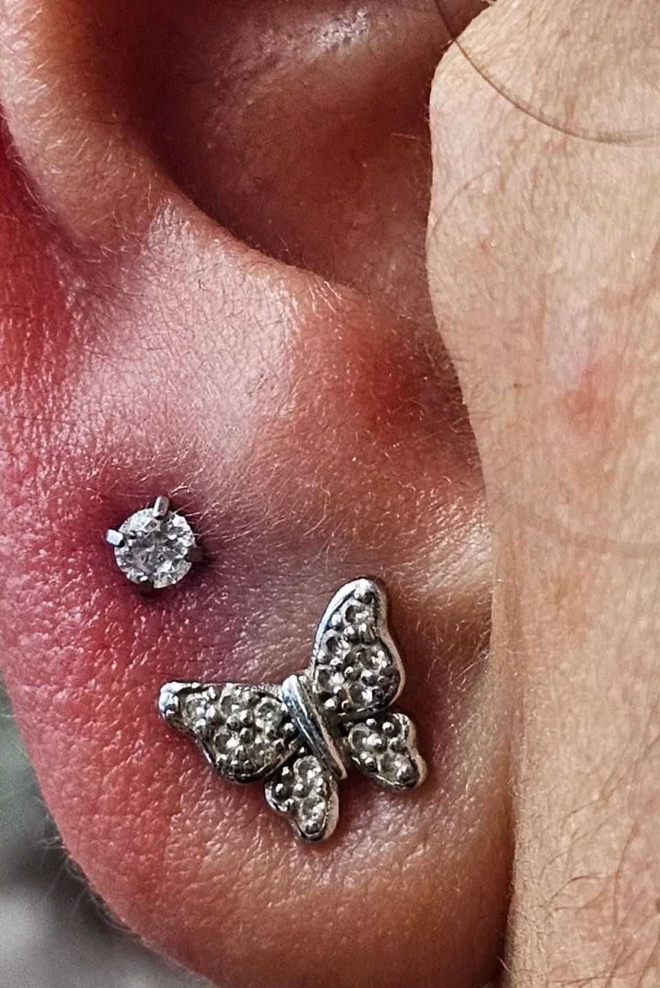 A close up of a person 's ear with a butterfly earring.