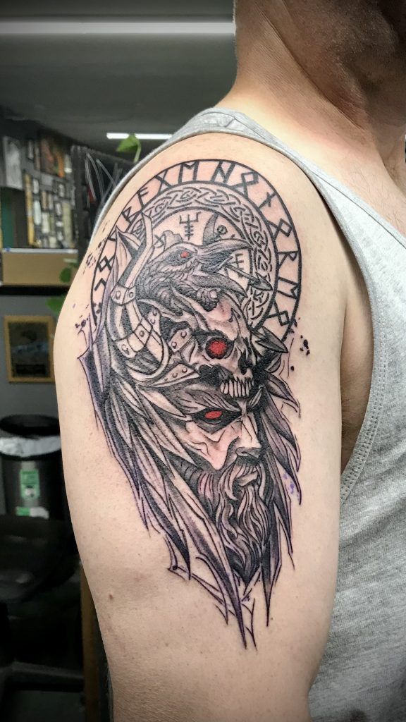 A man has a tattoo of a bearded man on his shoulder.