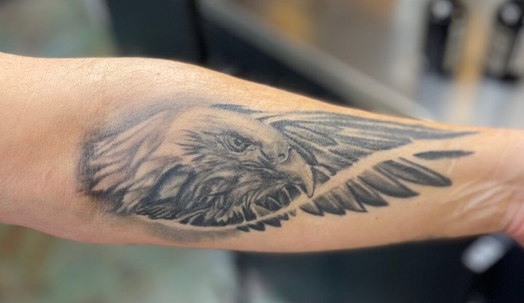 A person has a tattoo of an eagle on their forearm.