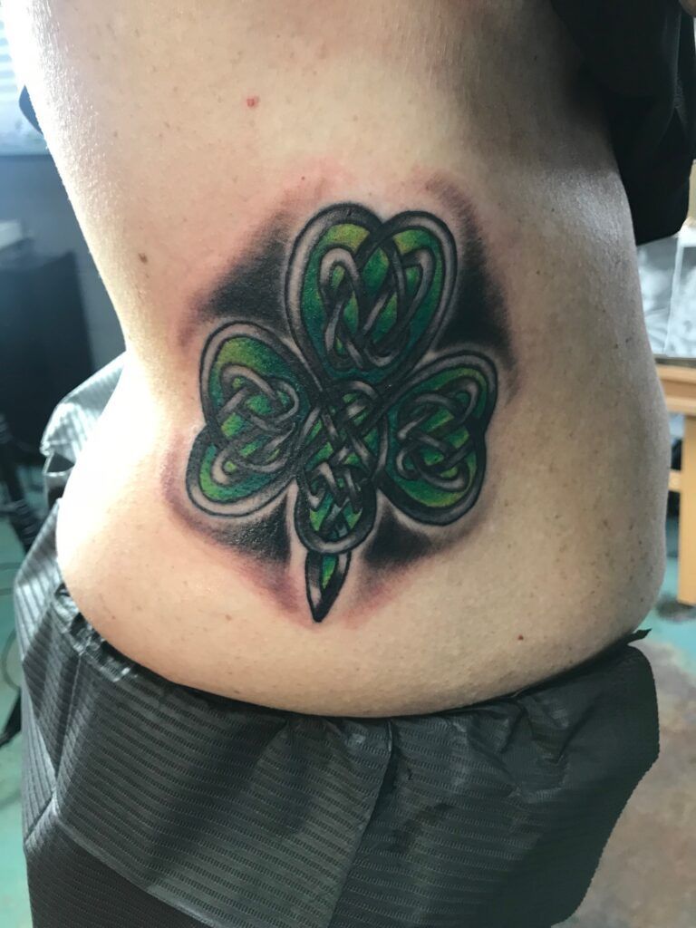 A woman has a clover tattoo on her side.