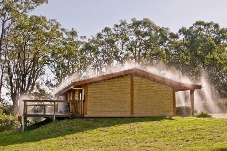 A brick house with trees in the background and smoke coming out of the roof