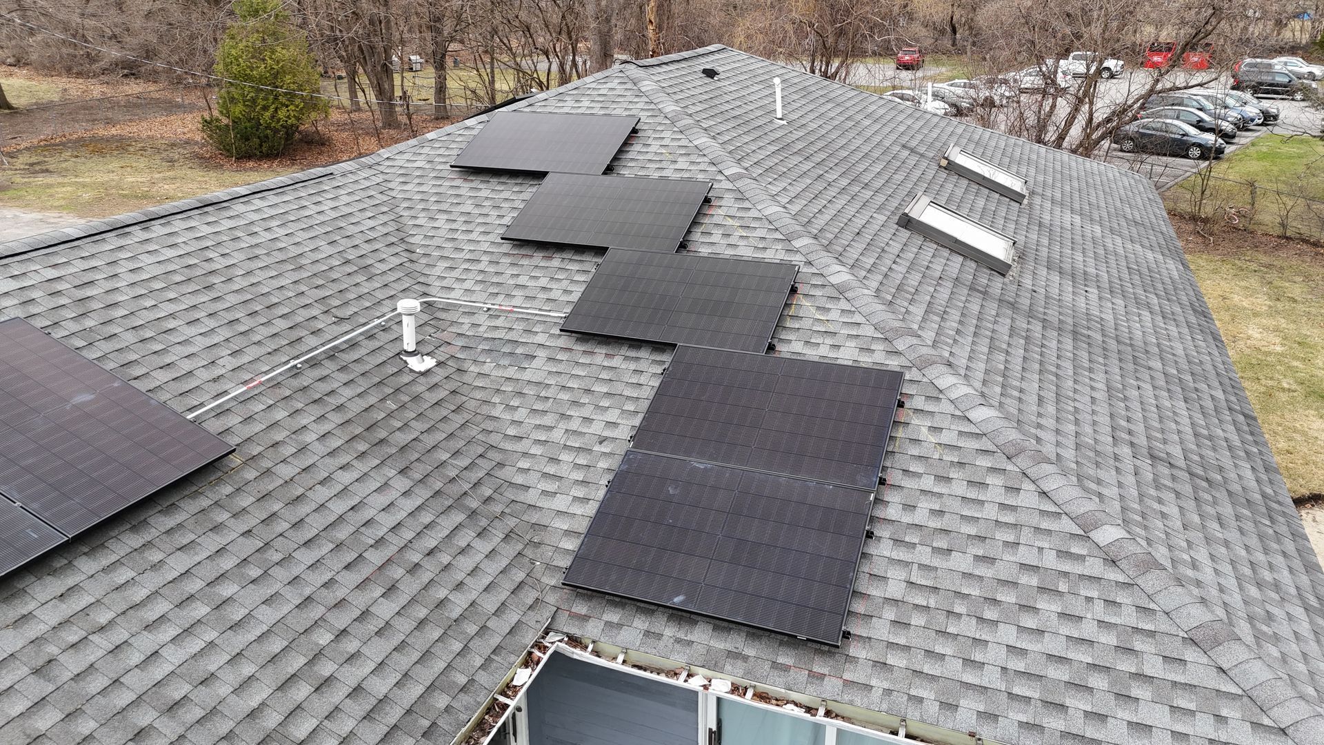 There are many solar panels on the roof of a house.