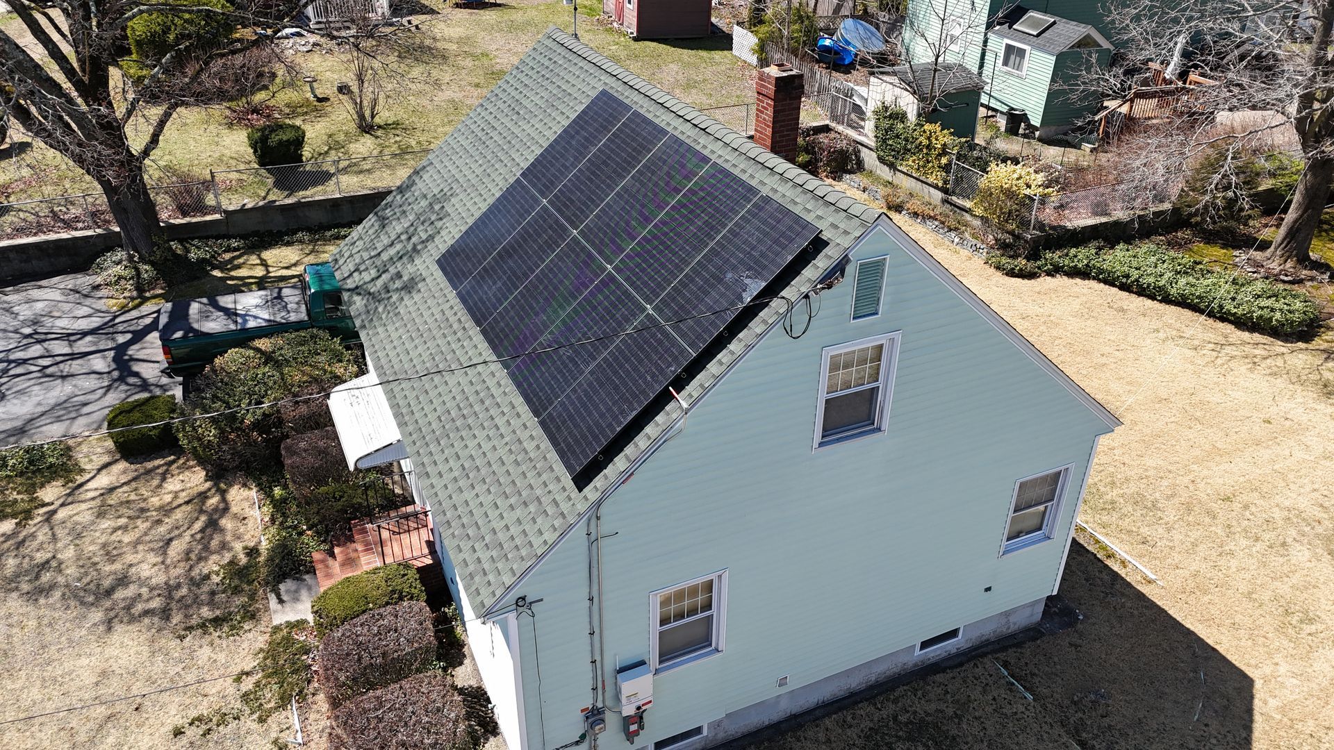 An aerial view of a house with solar panels on the roof.
