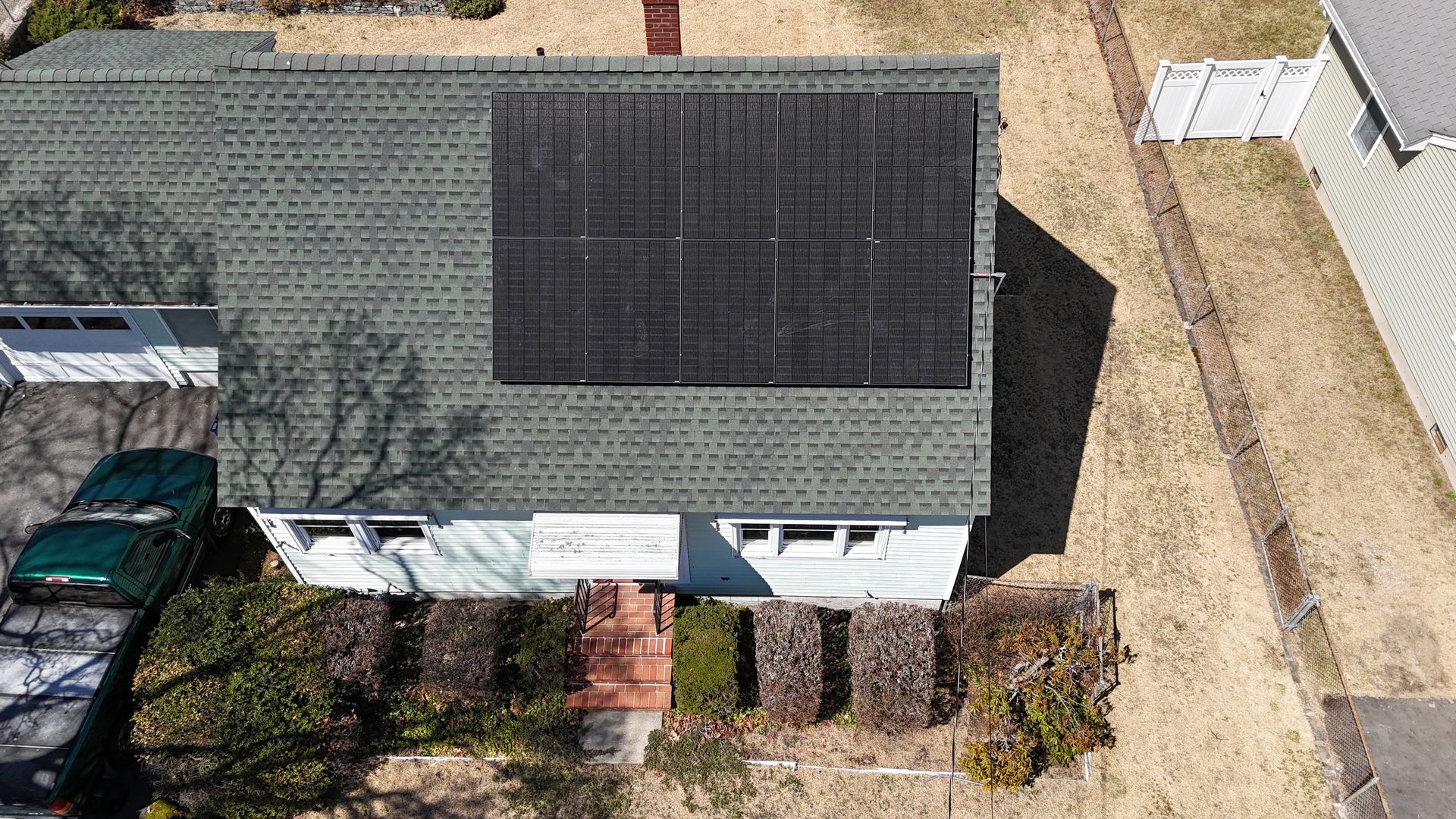 An aerial view of a house with solar panels on the roof.