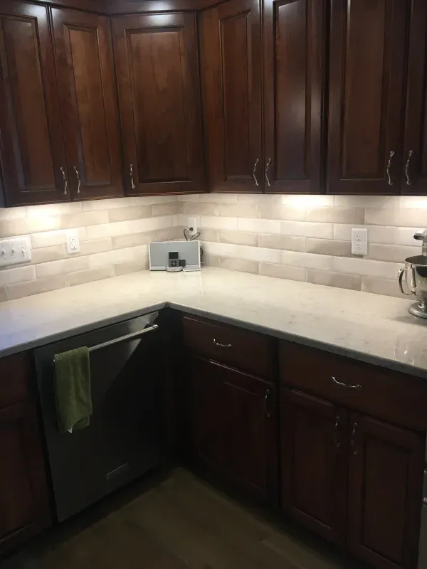 A kitchen with wooden cabinets and a stainless steel dishwasher.