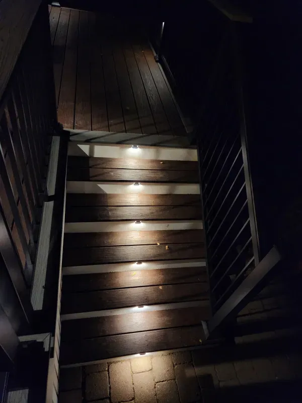 A set of wooden stairs with lights on them at night.