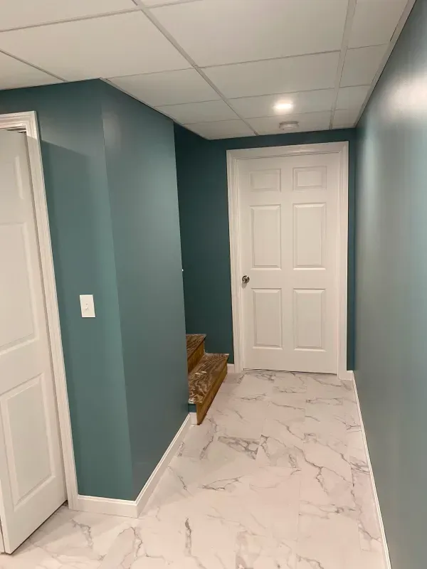 A hallway with blue walls and white doors in a basement.