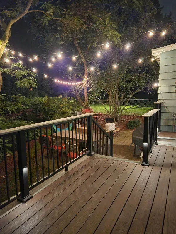 A deck with a railing and lights on it at night.
