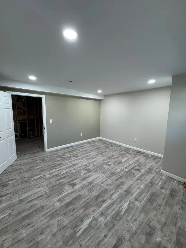 An empty basement with a wooden floor and white walls.