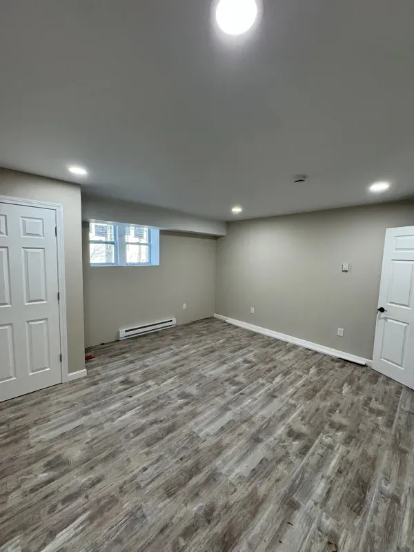 A large empty room with hardwood floors and a window.