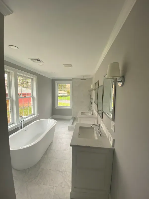 A bathroom with a bathtub , sink and mirrors.