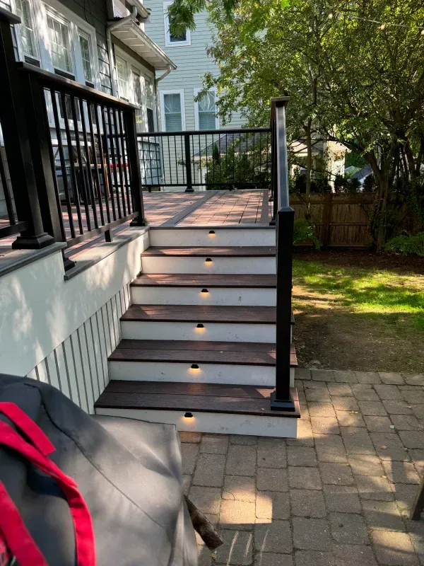 A deck with stairs leading up to it and a black railing.
