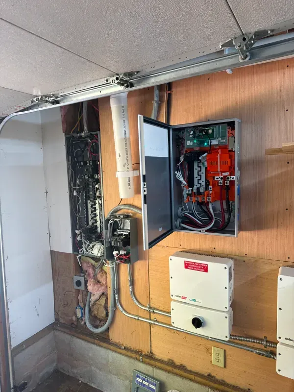 A electrical box is sitting on a wooden wall in a garage.