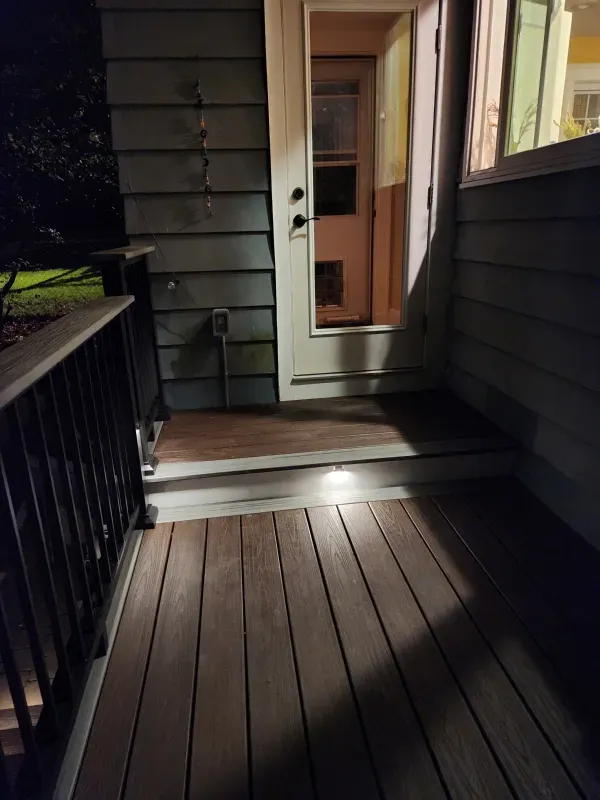 A porch with a wooden deck and stairs at night.