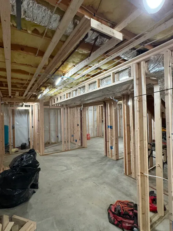 A basement under construction with wooden beams and a concrete floor.